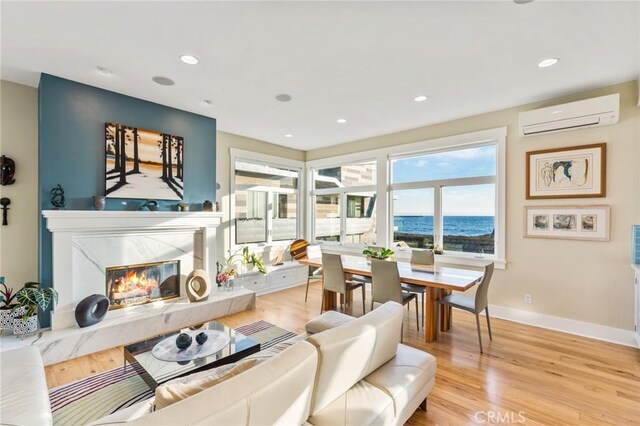 living room featuring a high end fireplace, light hardwood / wood-style floors, and a wall mounted AC