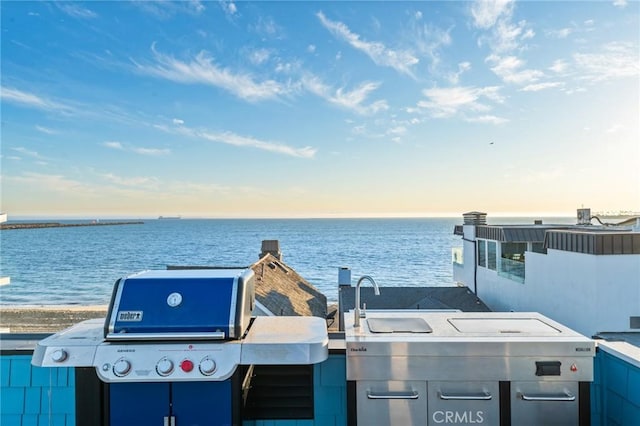 patio terrace at dusk featuring a water view, grilling area, and a sink