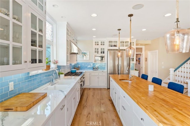 kitchen with white cabinetry, appliances with stainless steel finishes, decorative light fixtures, and sink