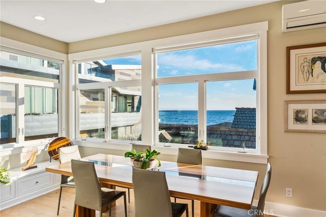 dining space with a water view, light wood-style floors, recessed lighting, and a wall mounted AC