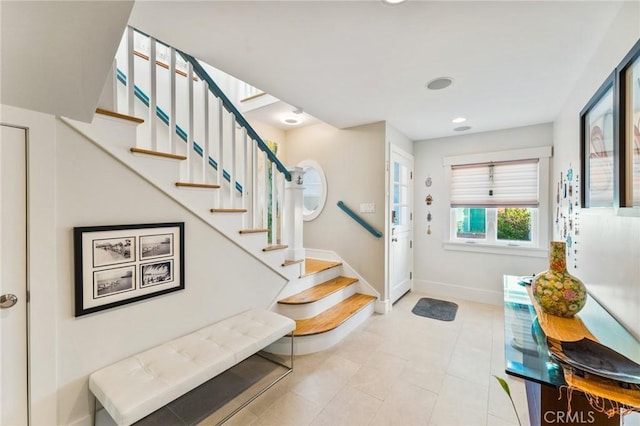 foyer entrance with stairs and baseboards