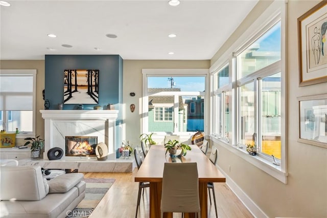 dining area with light wood-type flooring, a fireplace, baseboards, and recessed lighting