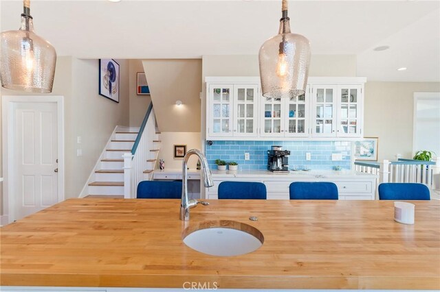 interior space featuring white cabinetry, decorative light fixtures, sink, and tasteful backsplash