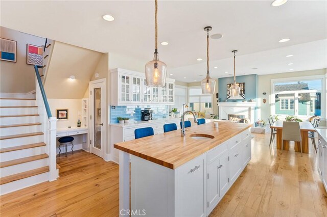 kitchen with white cabinetry, sink, decorative light fixtures, and a center island with sink