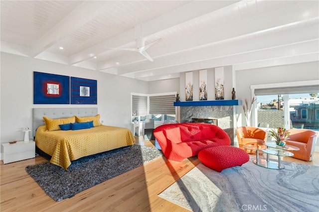 bedroom featuring a fireplace, beamed ceiling, and wood finished floors