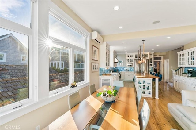 dining room featuring sink, an AC wall unit, and light wood-type flooring