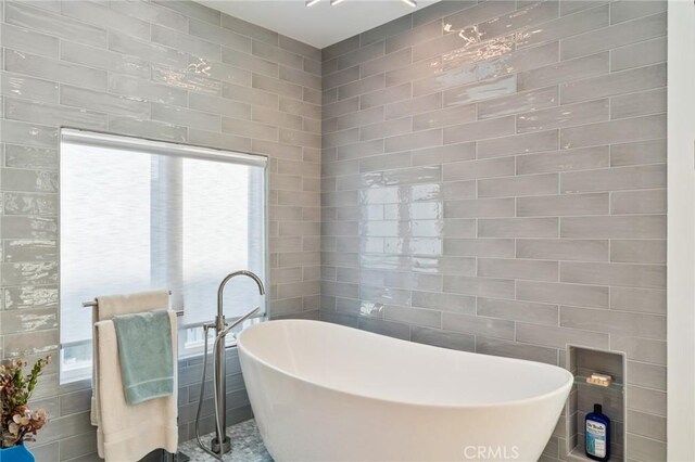 bathroom featuring a washtub and tile walls