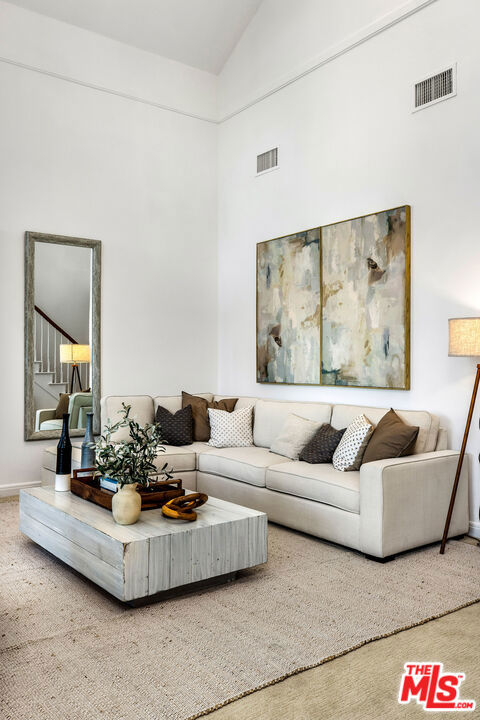 carpeted living room with high vaulted ceiling