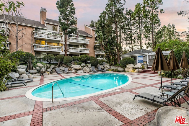 pool at dusk featuring a patio area