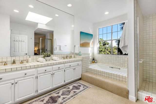 bathroom with vanity, a skylight, and separate shower and tub