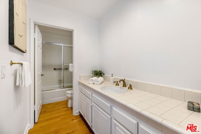 full bathroom featuring vanity, hardwood / wood-style flooring, bath / shower combo with glass door, and toilet