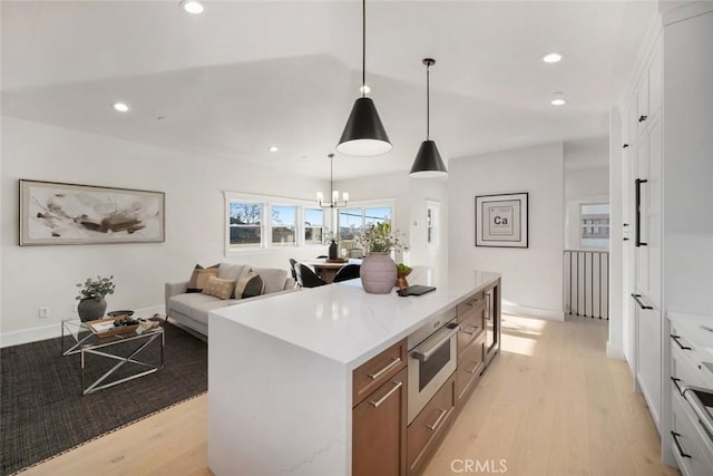 kitchen with white cabinets, a kitchen island, light wood-style flooring, and recessed lighting