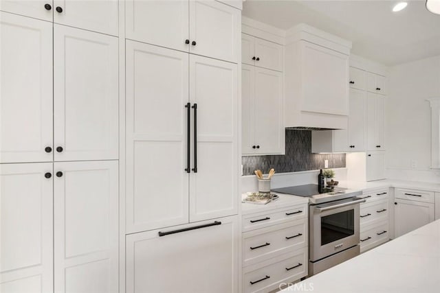 kitchen with light stone counters, electric range, white cabinets, and tasteful backsplash