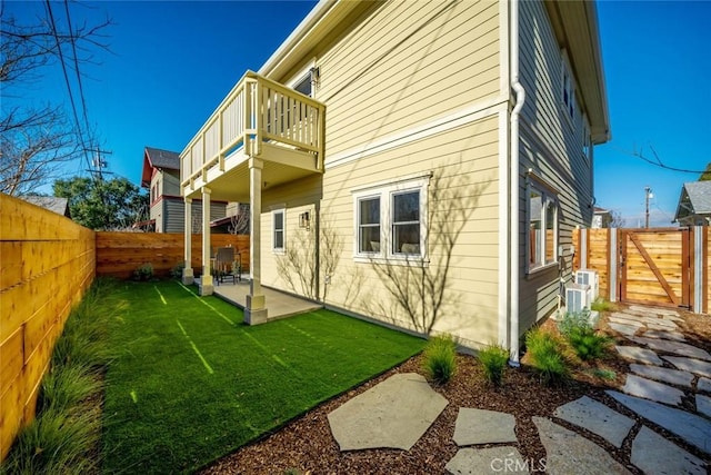 rear view of house featuring a patio area, a yard, and a balcony