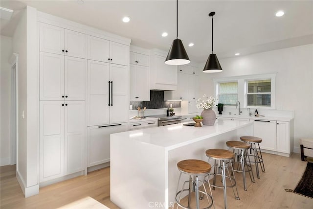 kitchen with light wood-type flooring, a center island, white cabinetry, and a kitchen breakfast bar