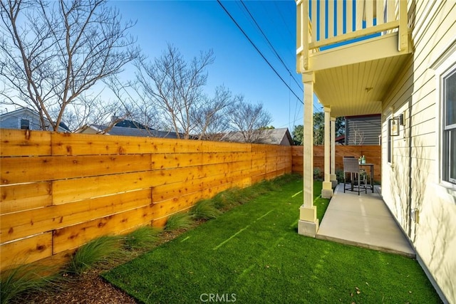 view of yard with a fenced backyard, a patio, and a balcony