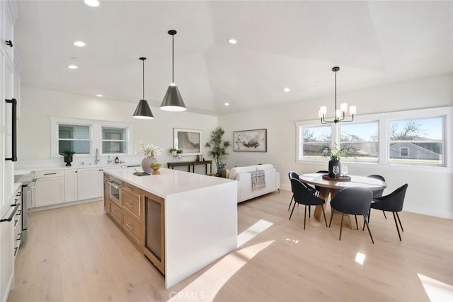 kitchen with a kitchen island, white cabinetry, light hardwood / wood-style flooring, and pendant lighting