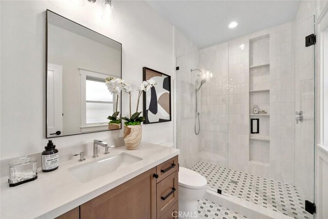 bathroom featuring vanity, toilet, and a shower with door