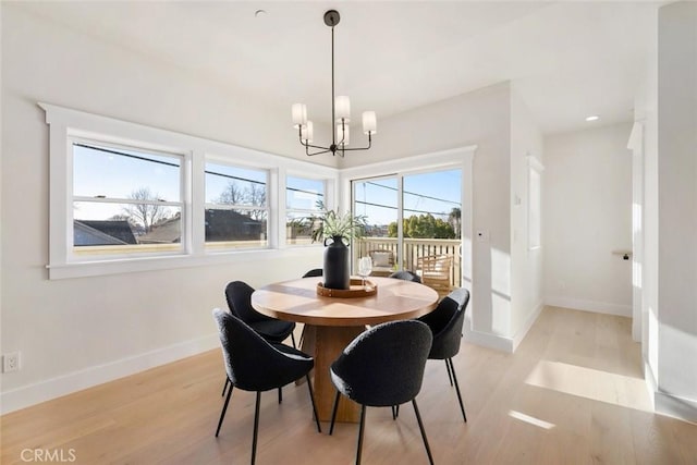 dining space with light wood-type flooring, baseboards, and a notable chandelier