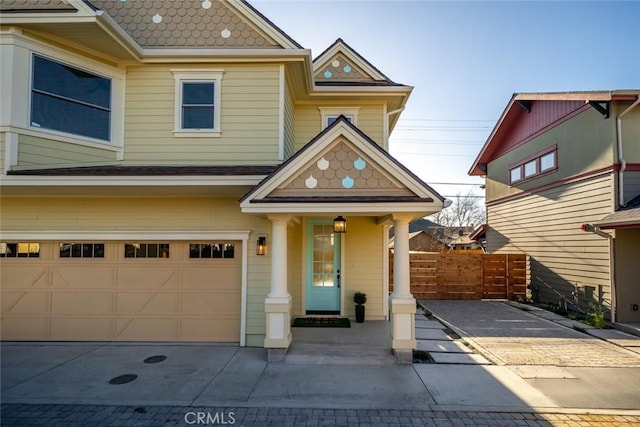 view of front of home featuring driveway, an attached garage, and fence