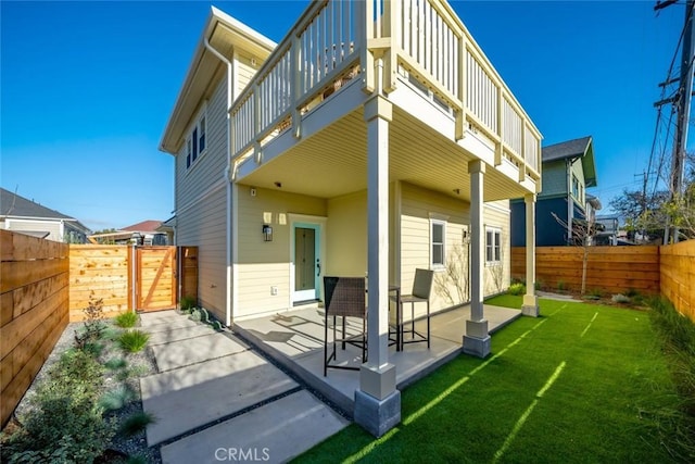 back of house featuring a patio, a balcony, and a lawn