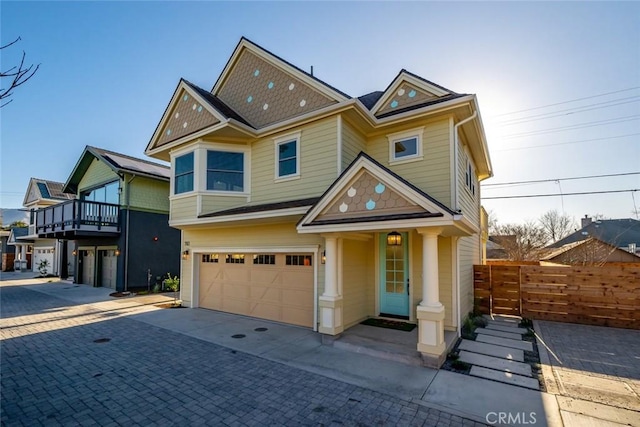 view of front of house with an attached garage, fence, and decorative driveway