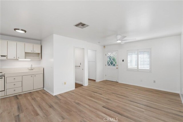 kitchen featuring ceiling fan, sink, exhaust hood, and light wood-type flooring