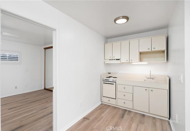 kitchen featuring white range with electric stovetop, sink, light hardwood / wood-style flooring, wall oven, and cream cabinetry