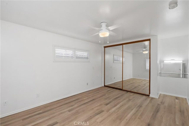 unfurnished bedroom with ceiling fan, multiple windows, a closet, and light wood-type flooring