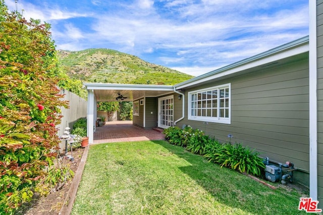 exterior space featuring ceiling fan, a mountain view, a yard, and a patio