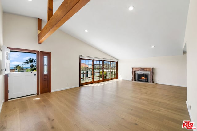 unfurnished living room with vaulted ceiling with beams, a premium fireplace, and light hardwood / wood-style floors