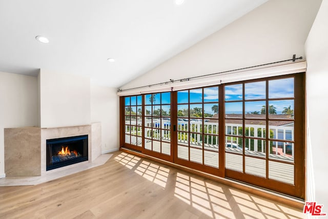 living room featuring light wood-type flooring, a high end fireplace, and plenty of natural light