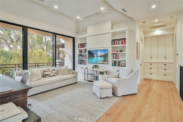 living room featuring light wood-type flooring and built in features