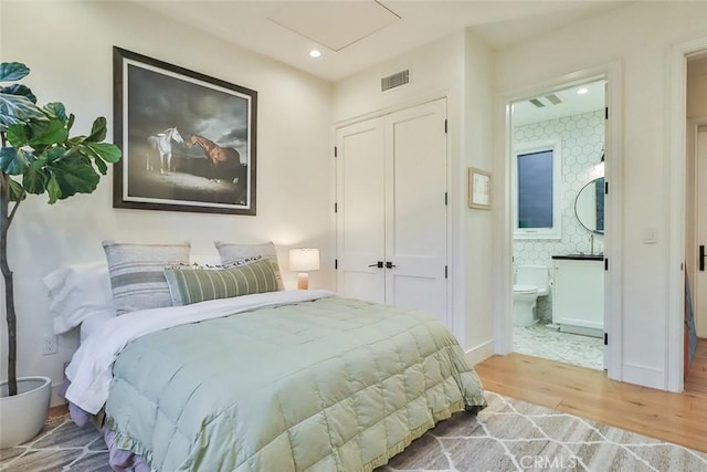 bedroom with sink, connected bathroom, and light hardwood / wood-style flooring