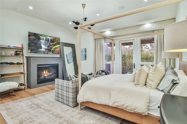 bedroom featuring lofted ceiling, light hardwood / wood-style floors, and access to outside