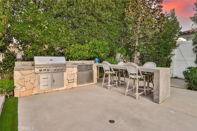 patio terrace at dusk featuring area for grilling