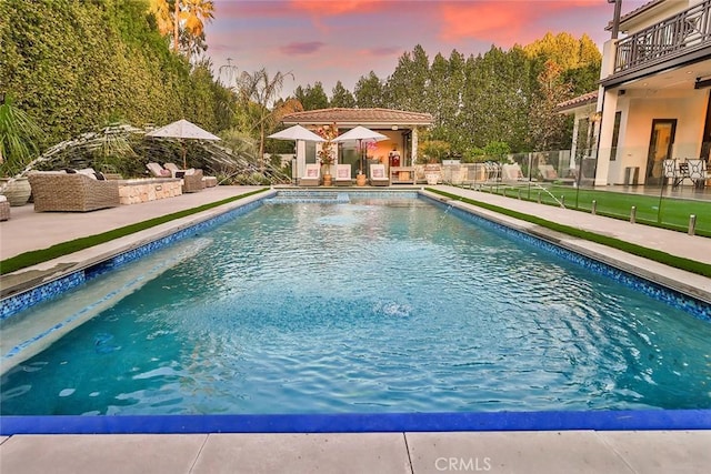 pool at dusk featuring a patio area