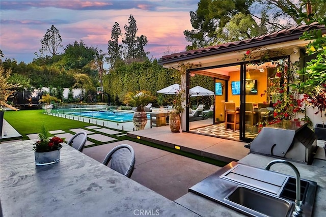 patio terrace at dusk featuring a lawn