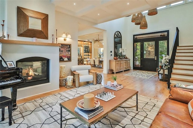 interior space featuring beam ceiling, light wood-type flooring, a multi sided fireplace, and coffered ceiling