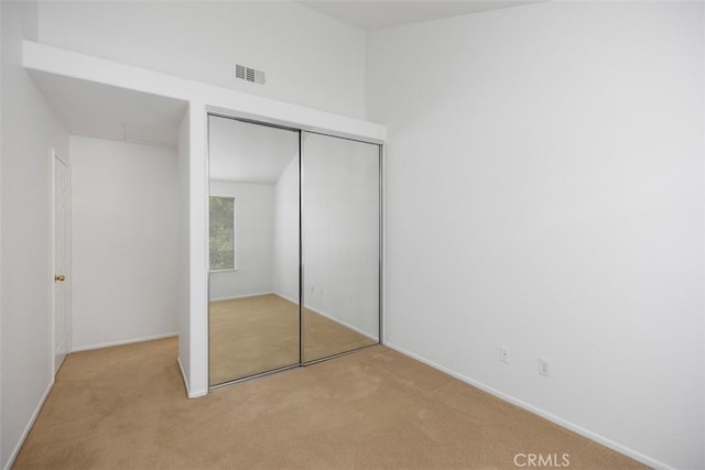 unfurnished bedroom featuring light colored carpet and a closet