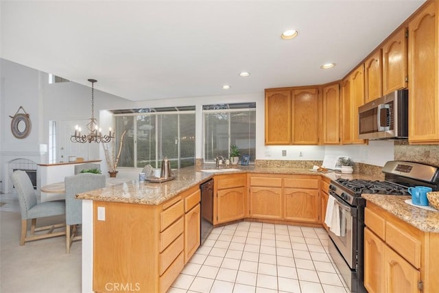 kitchen featuring pendant lighting, sink, a chandelier, light stone counters, and stainless steel appliances