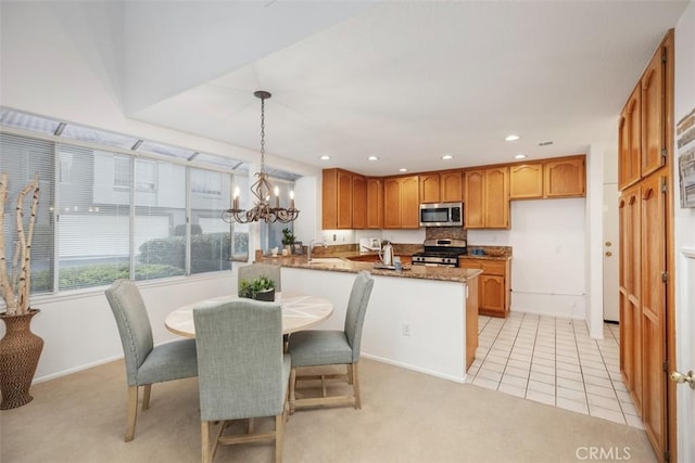 kitchen featuring light tile patterned flooring, appliances with stainless steel finishes, stone countertops, hanging light fixtures, and kitchen peninsula