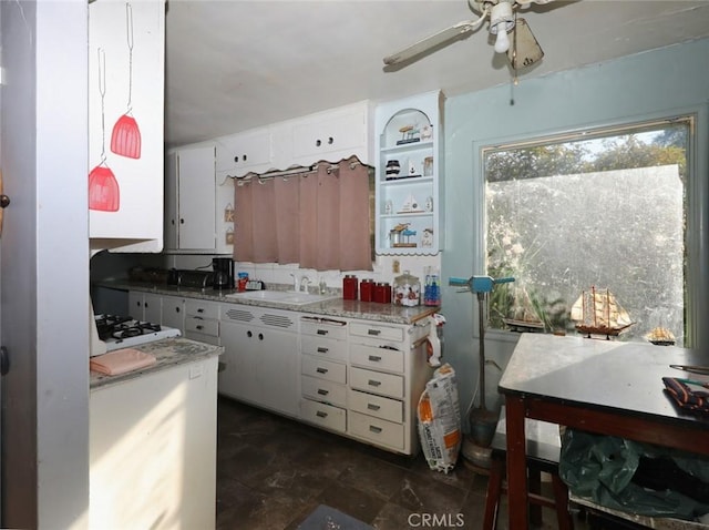 kitchen with sink, white cabinets, white gas cooktop, and light stone counters