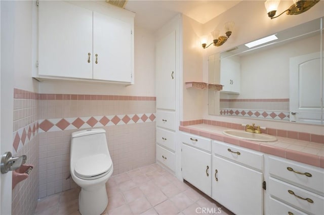 bathroom featuring toilet, vanity, tile walls, and tile patterned floors