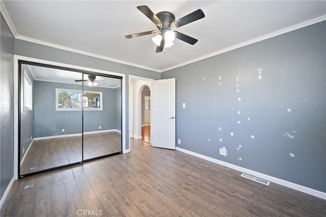 unfurnished bedroom with a closet, crown molding, hardwood / wood-style floors, and ceiling fan