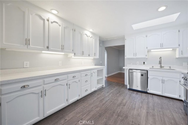 kitchen featuring a skylight, hardwood / wood-style floors, appliances with stainless steel finishes, white cabinets, and sink