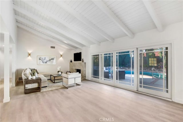 living room with lofted ceiling with beams, a premium fireplace, and light hardwood / wood-style floors