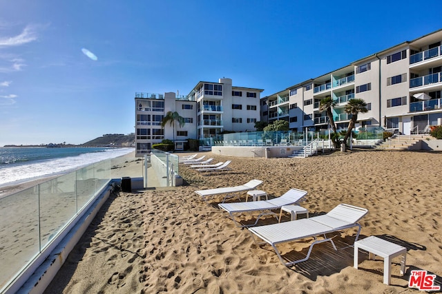 view of community with a water view and a beach view