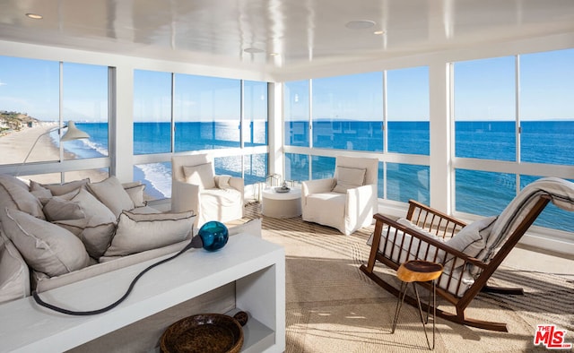 sunroom featuring a water view