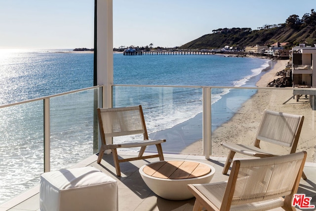 balcony with a water view and a view of the beach